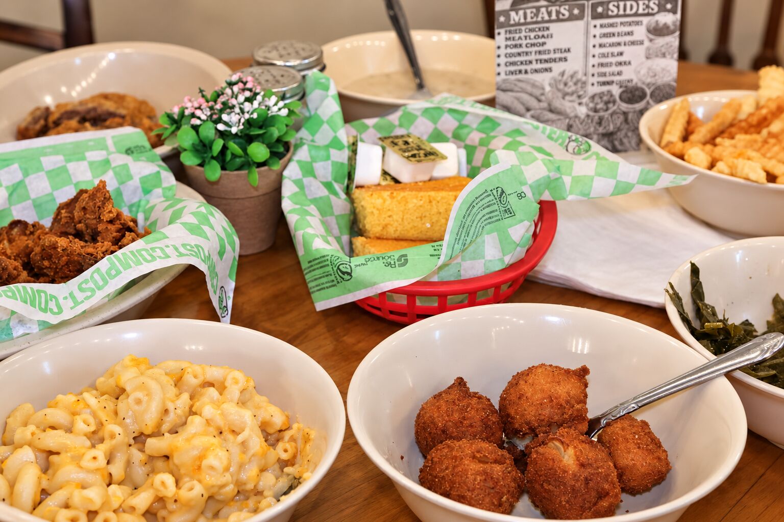 Family style spread on the table — macaroni and cheese, hush puppies, cornbread, fried chicken livers and turnip greens shared from the lazy Susan